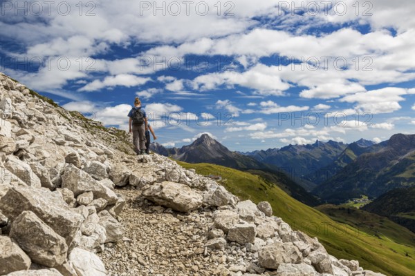 A person is hiking on a rocky path in an alpine landscape, Schröcken, Austria