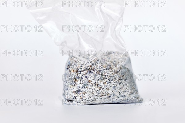 Plastic bag containing ash of a pet cat after cremation on white background