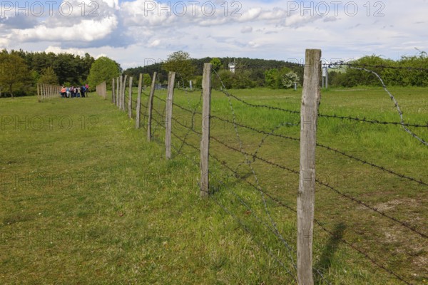 Partially reconstructed first border fence on the inner German border former zone border between West Germany Federal Republic and GDR East Germany with barbed wire between death strips, group of visitors on the left in the background, open-air museum museum Point Alpha, Rasdorf, Hesse, Geisa, Thuringia, Germany