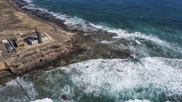 Aerial view from left lighthouse Faro Punta de Jandia at the southern tip of Jandia Peninsula, in the foreground white foam crowns on moving sea swell large high waves on reef edge beaming sea strong surf, Fuerteventura, Canary Islands, Canary Islands, Spain