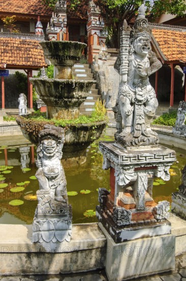Guardian figures in front of an old well in Brahma Vihara Arama Buddha Banjar Buddhist monastery, Banjar, Bali, Indonesia