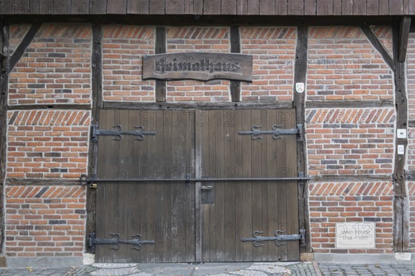 Wooden and brick gate of a medieval half-timbered house with rustic sign, Münsterland, North Rhine-Westphalia, Germany