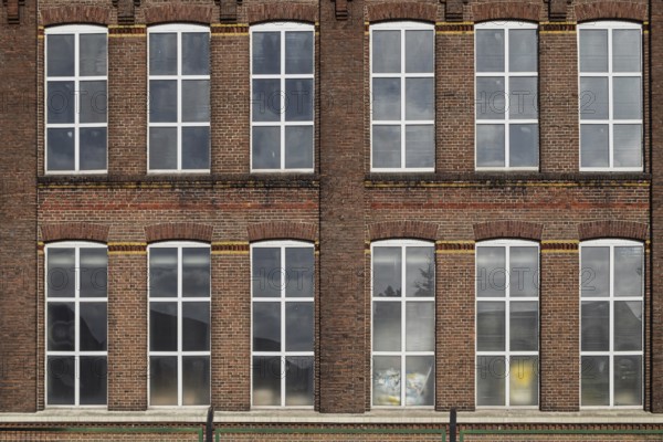 Symmetrical façade of an old brick building with large industrial windows, former Germania cotton mill, built in 1902 and a monument since 1995, Gronau-Epe, Münsterland, North Rhine-Westphalia, Germany