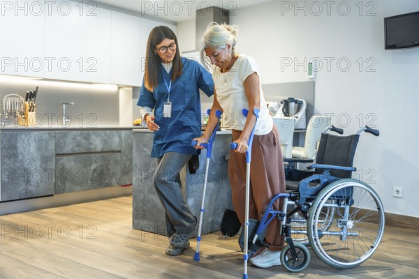 Professional caregiver helping an older woman with crutches, safely supporting her during a rehabilitation session in a modern home kitchen, overcoming mobility challenges