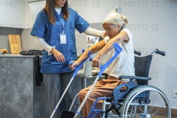 Professional caregiver assisting an elderly woman from a wheelchair, supporting her as she prepares to use crutches during a home rehabilitation session, promoting independence and recovery