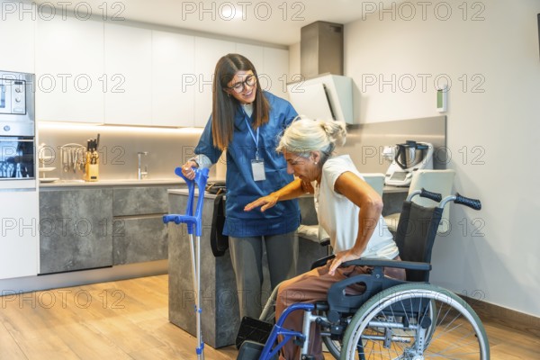 Young nurse providing assistance to an elderly woman safely moving from a wheelchair to crutches, focusing on home care support and rehabilitation in a modern kitchen
