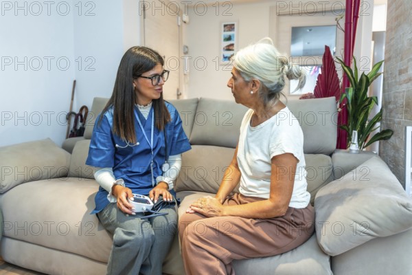 Healthcare professional checking blood pressure for an elderly woman during a home medical visit, providing essential care and support in her residence