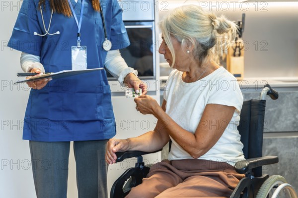 Nurse handing blister pack medication to a senior woman in a wheelchair at home, illustrating compassionate caregiver support, daily treatment and eldercare assistance