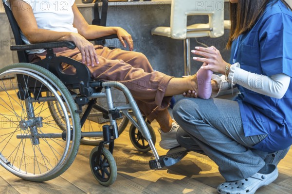 Physiotherapist providing physical therapy to a senior patient sitting in a wheelchair, offering gentle care and support for leg and foot rehabilitation