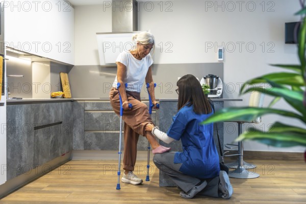 Healthcare professional guiding elderly woman with crutches during home physiotherapy session, supporting mobility, recovery and independence in a comfortable domestic setting