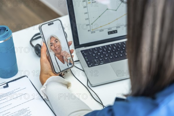 Woman having an online telemedicine consultation with a senior female doctor on a mobile phone, using technology for remote healthcare and patient care from home