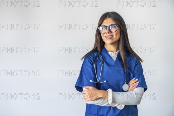 Young woman working as a professional healthcare provider, confidently standing with crossed arms, looking aside and smiling, embodying expertise and medical care
