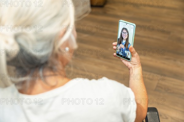 Senior woman is using a smartphone for a distant video consultation with a female doctor, experiencing modern healthcare and digital medicine services
