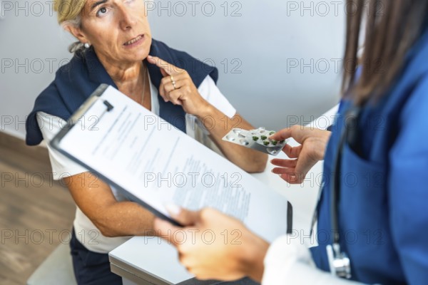 Medical professional discussing treatment options and handing blister pack of pills to an elderly female patient during a consultation, focusing on healthcare and medication