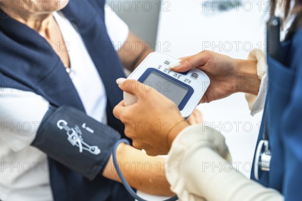 Healthcare professional checking a senior woman's blood pressure at home or in a clinic, focusing on preventive medicine, wellness, and monitoring vital signs for elderly care