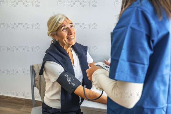 Nurse measuring blood pressure of smiling elderly woman during routine clinic checkup, highlighting preventative healthcare, monitoring, and compassionate primary care service