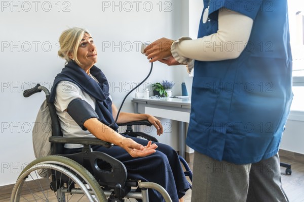 Nurse monitoring blood pressure of an elderly woman using a medical device while she is sitting in a wheelchair, illustrating healthcare, aging, and medical care concepts