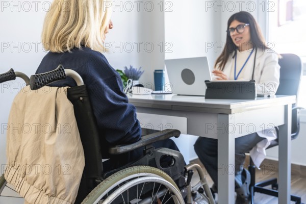 Patient in a wheelchair receiving medical advice from a female doctor during a healthcare consultation in a bright clinic setting, focusing on disability care and support