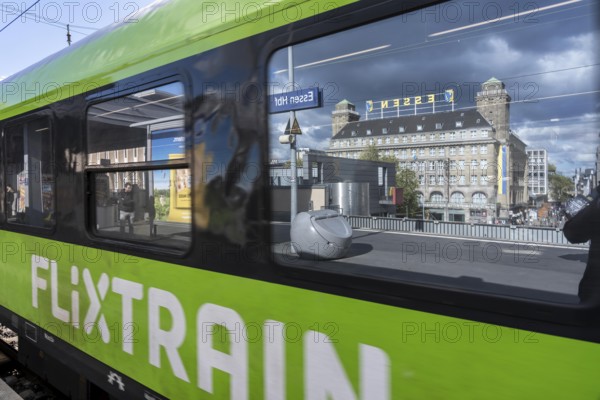 Flixtrain train on track 2 in Essen main station, reflection of the Handelshof building, city, platform in the window of the train, North Rhine-Westphalia, Germany