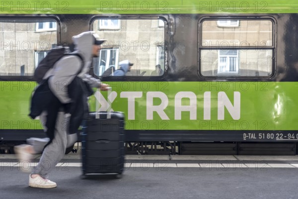 Flixtrain train on track 2 in Essen main station, passenger runs with luggage to reach his train, North Rhine-Westphalia, Germany