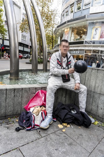 Man in public consumes laughing gas filled into a balloon with a gas cartridge, still legal intoxicant, pedestrian zone in Essen, North Rhine-Westphalia, Germany