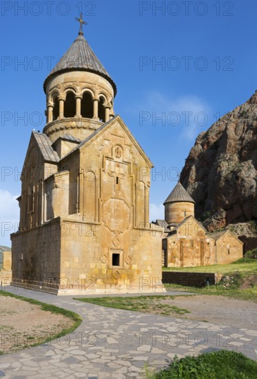 An ornate stone church with a paved path in the foreground and a blue sky ceiling, Noravank monastery, Surb Astvatsatsin mausoleum church and Surb Karapet baptism church, Noravank, Vayots Dzor province, Armenia, Caucasus