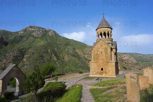 A chapel against a green mountain landscape under a blue sky, surrounded by nature, Noravank monastery, Surb Astvatsatsin mausoleum church, Noravank, Vayots Dzor province, Vayots Dzor, Armenia, Caucasus