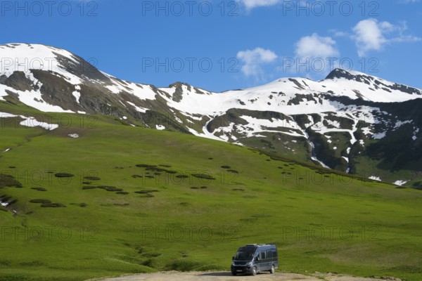 Snow and grassy hills stretch under a cloudy blue sky, Camper, Zagari Pass, Svaneti, Svaneti, Greater Caucasus, High Caucasus, Georgia