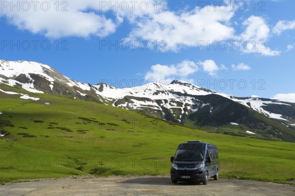 A motorhome stands in front of a green, snow-covered mountain landscape under a blue sky, Camper, Zagari Pass, Svaneti, Greater Caucasus, High Caucasus, Georgia