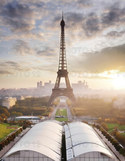 The Eiffel Tower is a tall structure in the background of a city. The sky is cloudy and the sun is setting, creating a moody atmosphere, AI generated