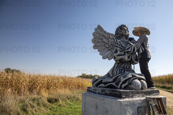 Chandler, Minnesota - Artist Primi Monteiga re-paints her concrete sculpture of an angel in the midst of Minnesota cornfields. Born in Spain, Monteiga grew up in Venezuela where she is well known for her art. She has been living in rural Minnesota since 2010