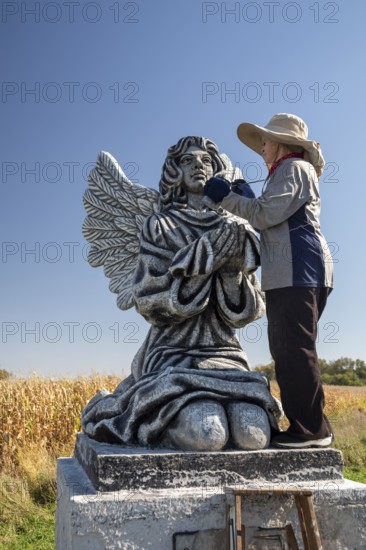 Chandler, Minnesota - Artist Primi Monteiga re-paints her concrete sculpture of an angel in the midst of Minnesota cornfields. Born in Spain, Monteiga grew up in Venezuela where she is well known for her art. She has been living in rural Minnesota since 2010