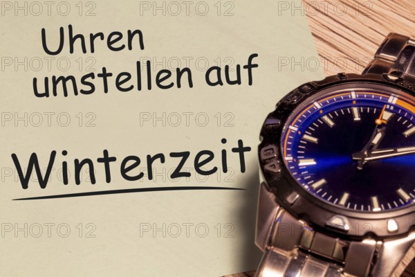 (photo montage) Time change winter time: close-up of a wristwatch and a note with the text CHANGE WATCHES TO WINTER TIME
