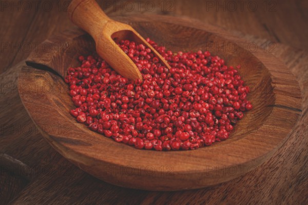 Bright red peppercorns, in a wooden bowl, with a small wooden tray
