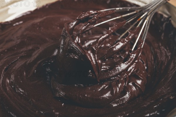 A bowl of chocolate dough, a whisk for whipping, baking, structure and consistency, homemade, top view, no people