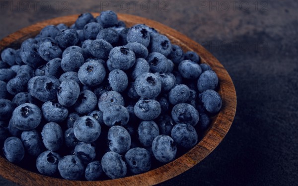 Fresh blueberries, in a wooden bowl, on the table, top view, close-up, no people