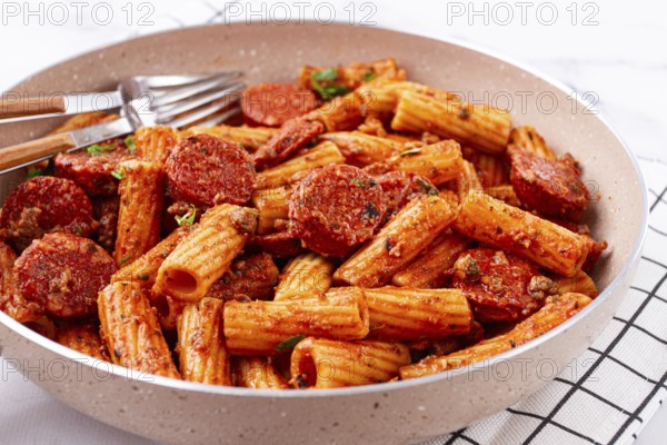 Rigatoni pasta with spicy sausage, and rich tomato sauce served, on a white plate, homemade