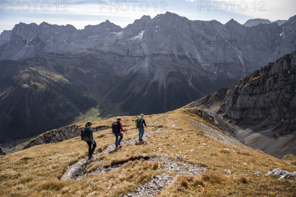 Three hikers on hiking trail, hiking to Gamsjoch, behind Dreizinkenspitze and Laliederer Wand, eastern Karwendel, Tyrol, Austria