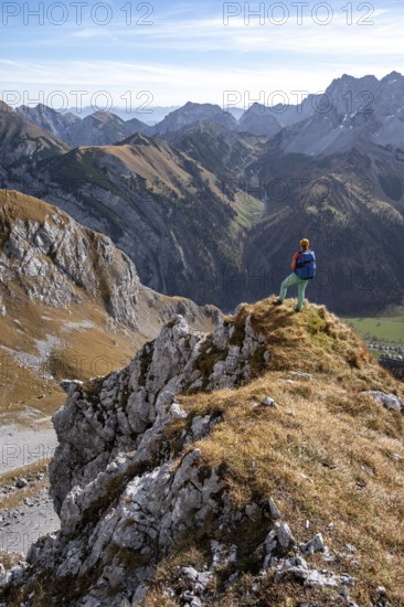 Hiker stands on a rock and looks into Ta, hiking to Gamsjoch, down the Ahornboden valley, eastern Karwendel, Tyrol, Austria