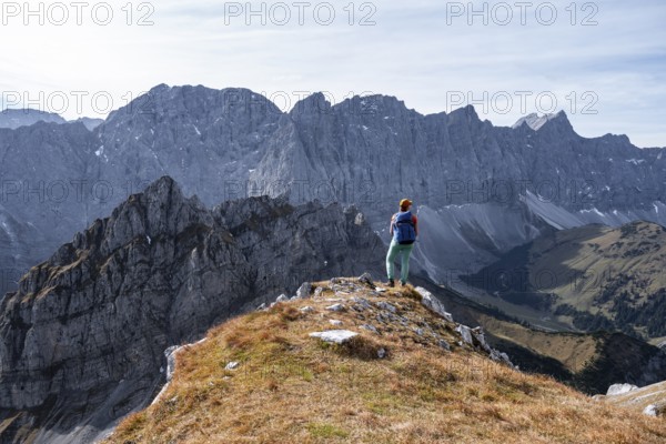 Hiker stands on a rock and looks at Laliederer Wand, hiking to Gamsjoch, down the Ahornboden valley, eastern Karwendel, Tyrol, Austria