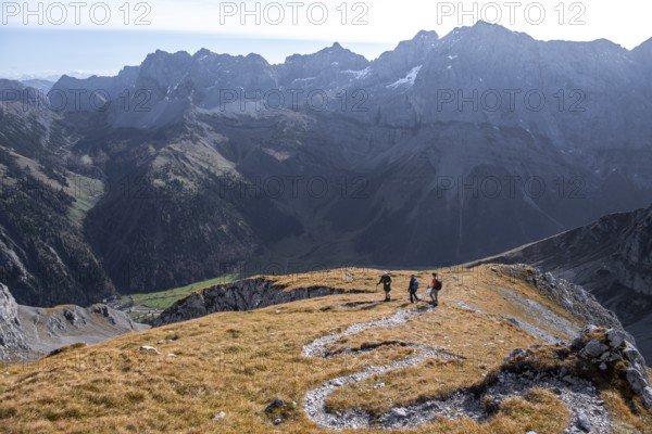 Three hikers descending, hiking trail with serpentines from Gamsjoch, dramatic rock faces of Hochglück in the back, eastern Karwendel, Tyrol, Austria