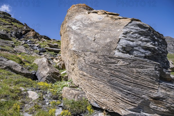 Large rock in the foreground shows fascinating rock structures under a blue sky, Valais Alps, Valais, Switzerland