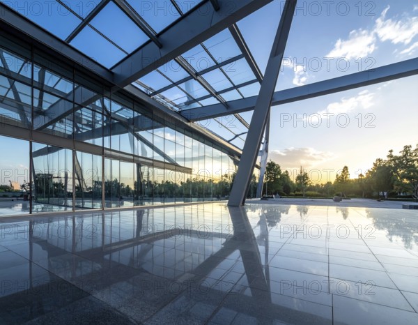 Modern architectural framework with glass and steel structure, glass facade with a greed of steel arrows, blue sky with a soft golden light of a sunrise, AI generated