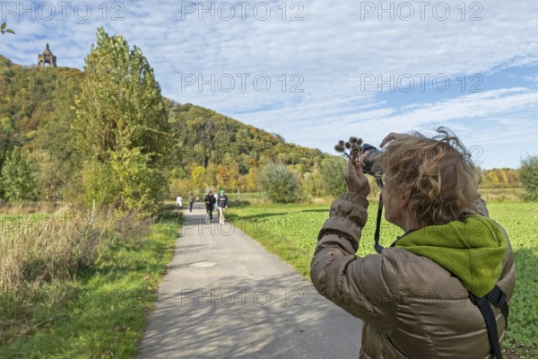 Woman photographing Kaiser Wilhelm monument, mountain, forest, path, Porta Westfalica, North Rhine-Westphalia, Germany