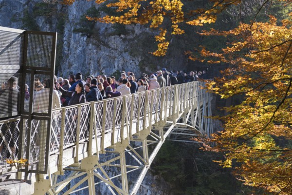 Group of people on Marienbrücke near Neuschwanstein, surrounded by autumn trees and rocks, Schwangau near Füssen, Ostallgäu, Allgäu, Bayern, Germany