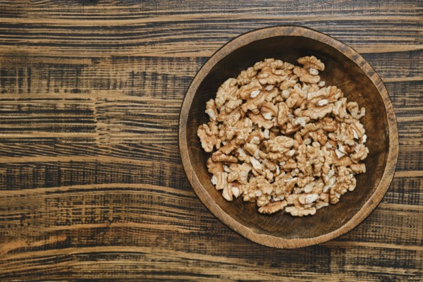 A wooden bowl with peeled walnuts, showcasing their rich texture and natural color on a rustic wooden table