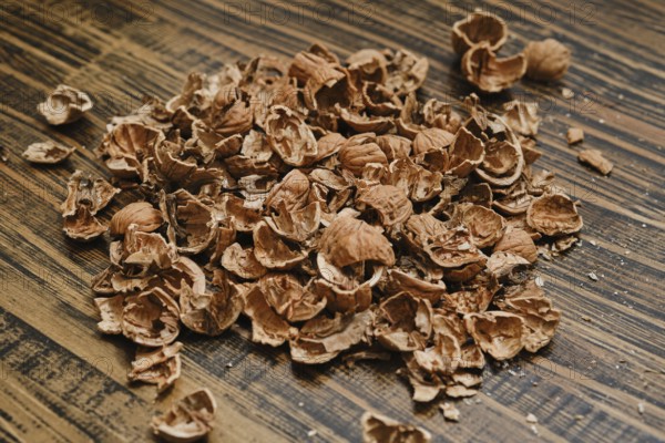 Brown nutshells are scattered on a wooden table, showing remnants of a recent snack. The natural texture of the shells contrasts with the smooth wood, creating an organic scene