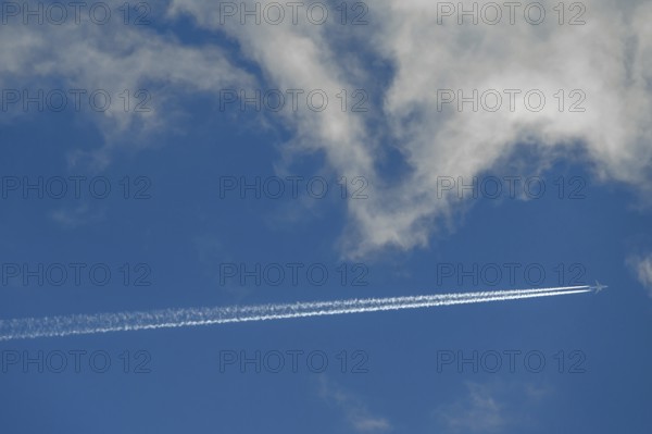 Passenger plane with contrails on a cloudy sky, Bavaria, Germany