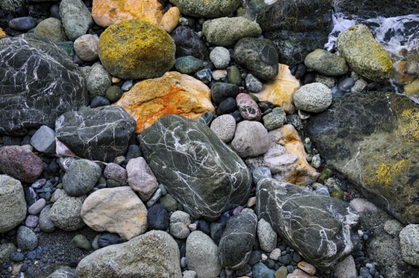 Colourful pebbles of various sizes with different patterns, on a beach in Liguria, Italy