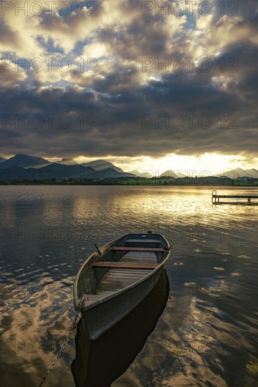 Rowing boat on Hopfensee in Allgäu at sunset in Hopfen am See, Bavaria, Germany